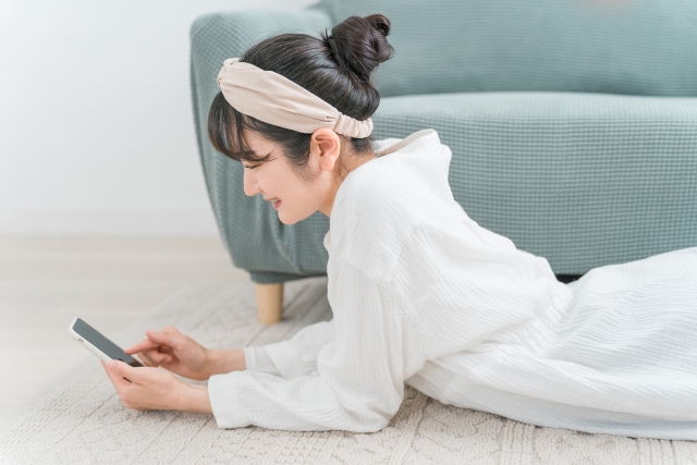 スマホを見てくつろいでいる女性の写真
